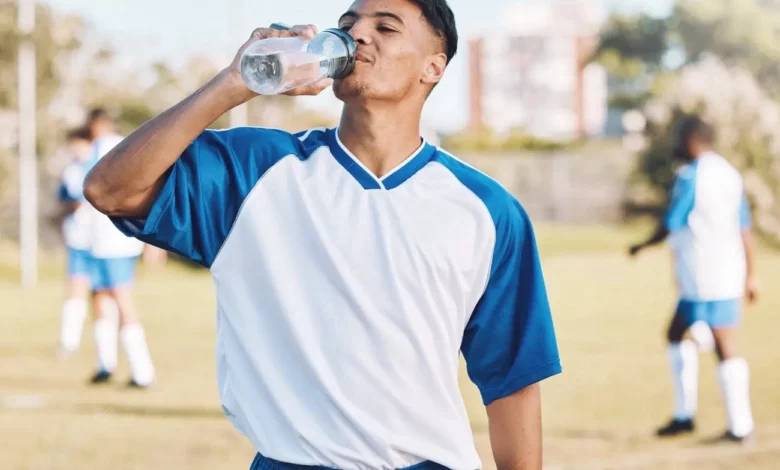 Footballeur qui boit de l'eau sur un terrain